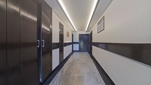 A hallway with dark wooden doors, a marble floor, and a ceiling with recessed lighting. - Treebo The Royal Taj (Agra)