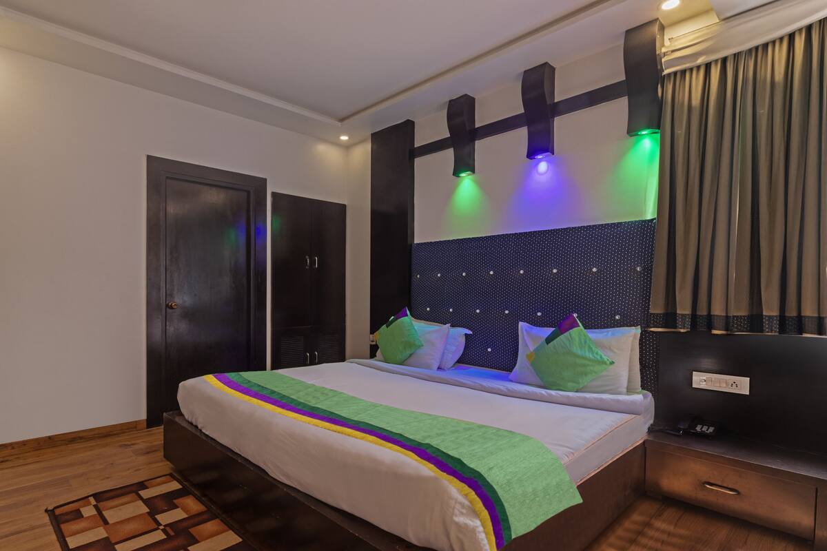 A hotel room with a bed, a desk, a wardrobe, and a nightstand.