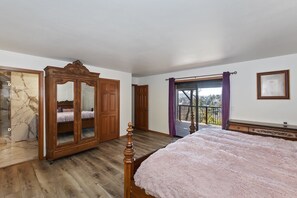Relax in a spacious bedroom with a large bed, a wardrobe, and a balcony offering a view of the surrounding landscape.