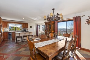 Enjoy meals in this stylish dining area with a large table, classic chairs, and a modern kitchen.
