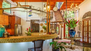 A spacious kitchen with a stone countertop, wooden cabinets, and a hanging light fixture. - Experience the Pure Life in the Private Jungle Paradise of Ojochal  (Provincia de Puntarenas)