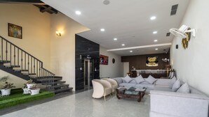 A modern living room with a staircase, a sofa set, and a reception area. - Treebo Omnibliss (Dera Bassi)
