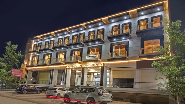 A multi-story hotel with balconies, a sign for 'Hotel Omnibliss', and cars parked in front. - Treebo Omnibliss (Dera Bassi)
