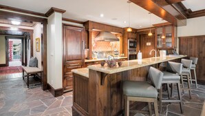 A spacious kitchen with a large island, wooden cabinetry, and a stone floor. - Cozy retreat at One Willow Bridge Road in Vail Village (Vail)