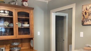 A kitchen with wooden cabinetry, a two-tiered metal serving tray, and a wall-mounted clock. - Cozy up at Foxtrot Inn! 
Immaculate! Outdoor Grain Bin BBQ area! Dog friendly!  (Cunningham)