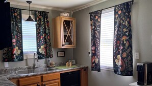A kitchen with granite countertops, wooden cabinets, a built-in dishwasher, a coffee maker, and a ceiling fan. - Cozy up at Foxtrot Inn! 
Immaculate! Outdoor Grain Bin BBQ area! Dog friendly!  (Cunningham)