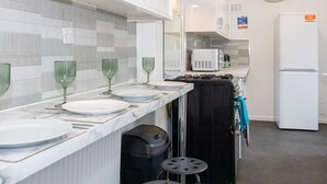 Una cocina moderna con armarios blancos, una estufa negra y un refrigerador blanco.