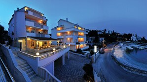 Ein mehrstöckiges Hotel mit Balkonen, einer überdachten Außenbereich-Sitzgelegenheit und Blick aufs Meer.