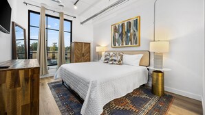Un dormitorio moderno con una cama grande, un escritorio de madera y vistas al exterior.