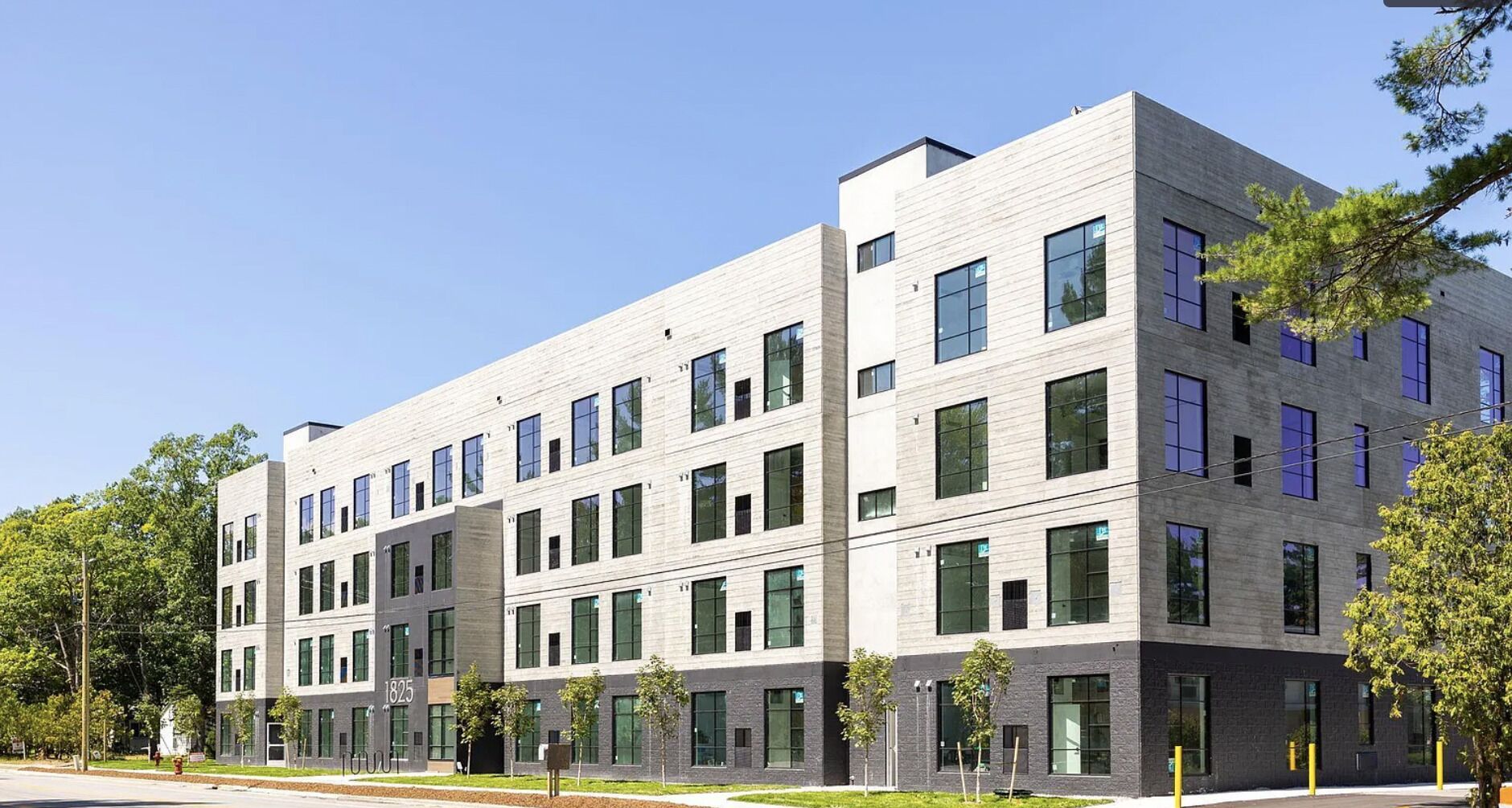 A modern multi-story building with a flat roof, large windows, and a mix of light and dark facade materials.