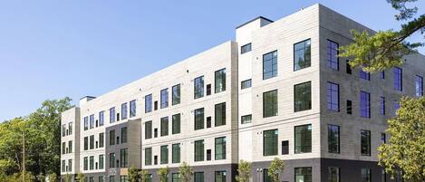 A modern multi-story building with a flat roof, large windows, and a mix of light and dark facade materials.