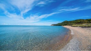 Una playa despejada con aguas tranquilas y una costa distante.
