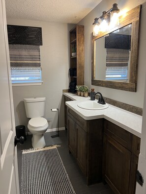 A bathroom with a toilet, sink, mirror, and a small window with blinds. - Stockyards ,Dickies, Cowtown Coliseum, 7th Street Close to All !! (Fort Worth)