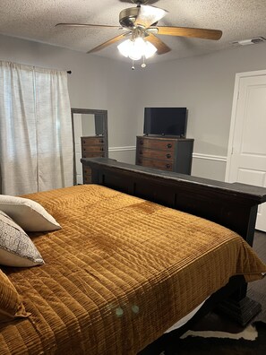 A bedroom with a bed, a dresser, a television, and a ceiling fan. - Stockyards ,Dickies, Cowtown Coliseum, 7th Street Close to All !! (Fort Worth)