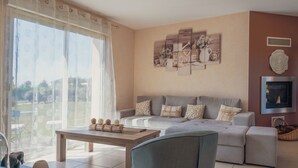Una sala de estar con un sofá, una mesa de centro y un ventanal con cortinas translúcidas.
