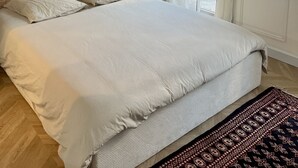 Un dormitorio con una cama grande, paredes oscuras y vistas al exterior.