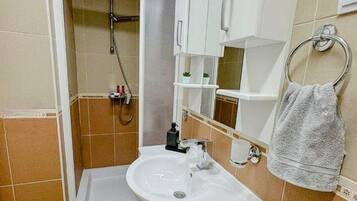 Een badkamer met douche, wastafel en toilet.