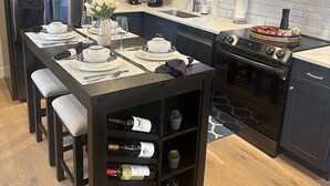 Een moderne keuken met donkere kastjes, roestvrijstalen apparatuur en een eethoek voor zes personen.