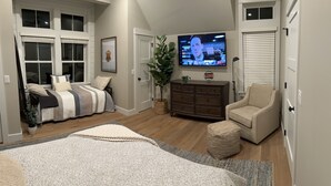 Een slaapkamer met een bed, een dressoir, een televisie en een stoel.