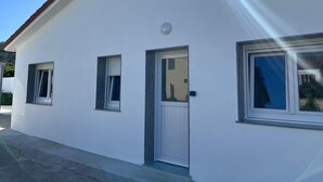 A white building with a red roof, a door, and three windows.