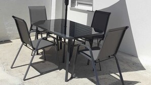 An outdoor patio with a table and chairs, an umbrella, and a view of buildings in the background.