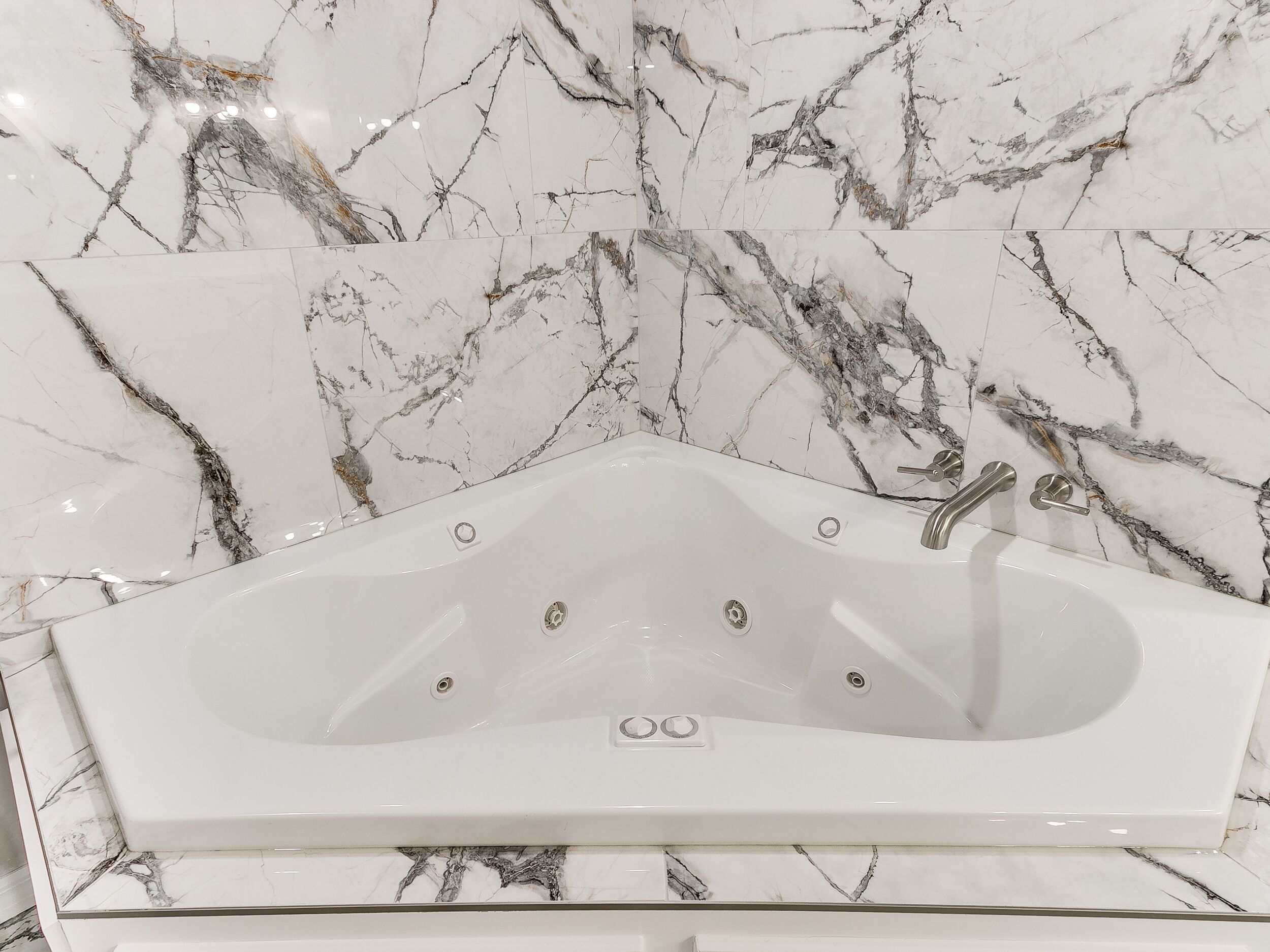 Ein modernes Badezimmer mit einer freistehenden Badewanne, Marmorwänden und einer eleganten Armatur.