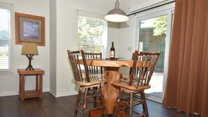 Un comedor con una mesa y sillas de madera, una lámpara y un cuadro en la pared.