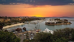 A coastal marina with boats docked, a pier, and a hilly landscape in the background. - • Book HARBOR VIEW • Luxury 3BR • Panoramic Ocean & Harbor Views (Dana Point)