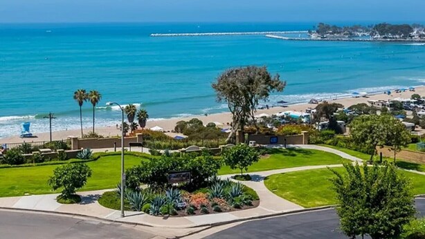 A coastal view with a beach, a clear sky, and a well-maintained park area. - • Book HARBOR VIEW • Luxury 3BR • Panoramic Ocean & Harbor Views (Dana Point)