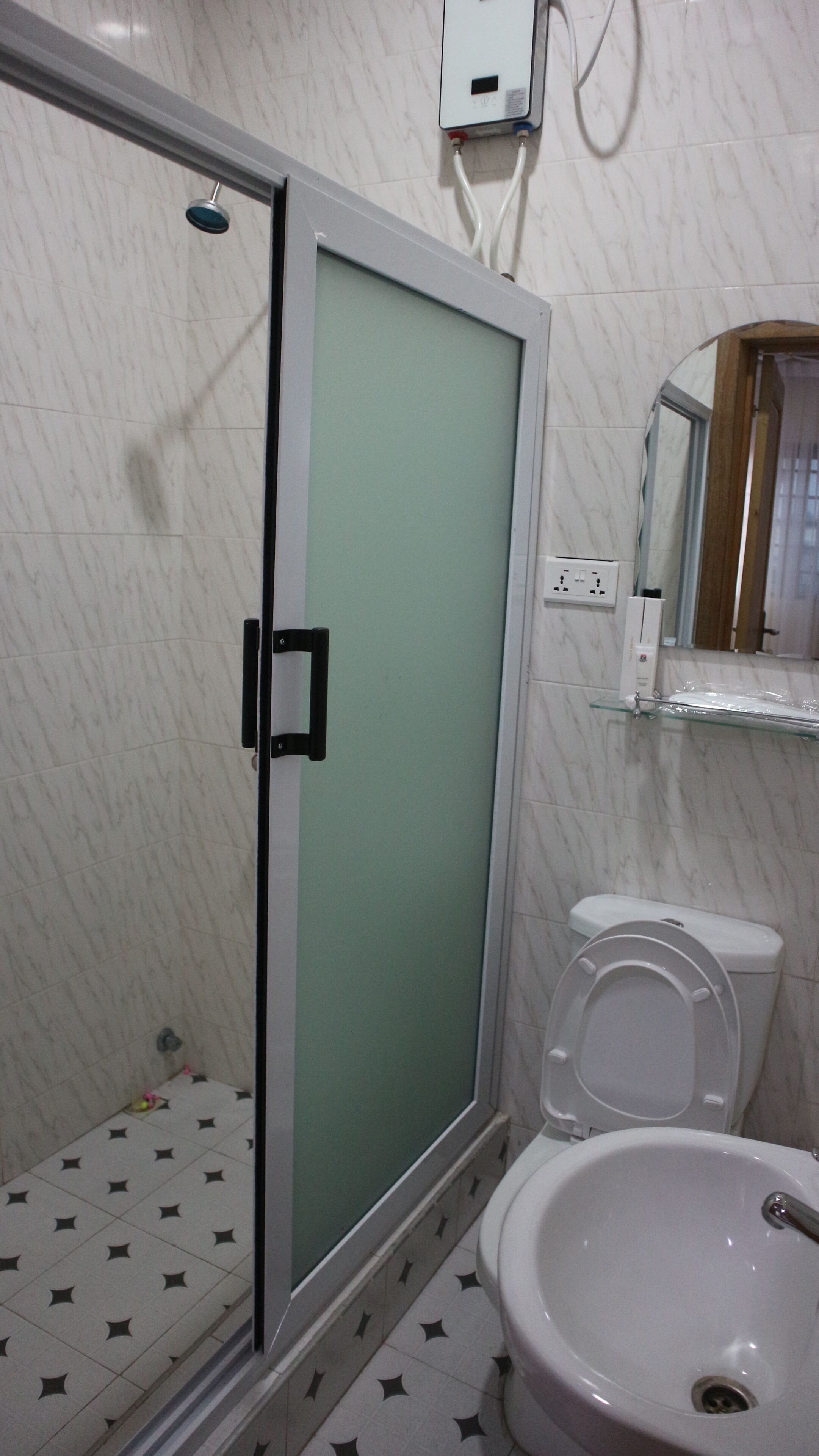 Un baño con cabina de ducha de vidrio, inodoro y lavamanos.