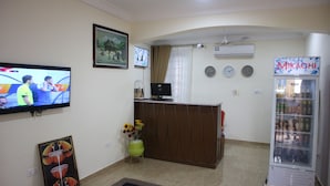 Un'area reception con televisore, orologio, distributore automatico e un quadro appeso al muro.