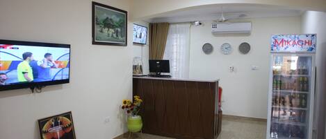 A reception area with a TV, a clock, a vending machine, and a framed picture on the wall.
