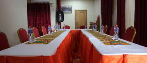 A conference room with a long table, red curtains, and water bottles.