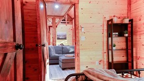 Ein Holzinnenraum mit einem Bett, einem Sofa und einem Bücherregal.