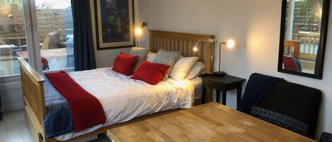 A bedroom with a bed, bedside table, and a wooden table.