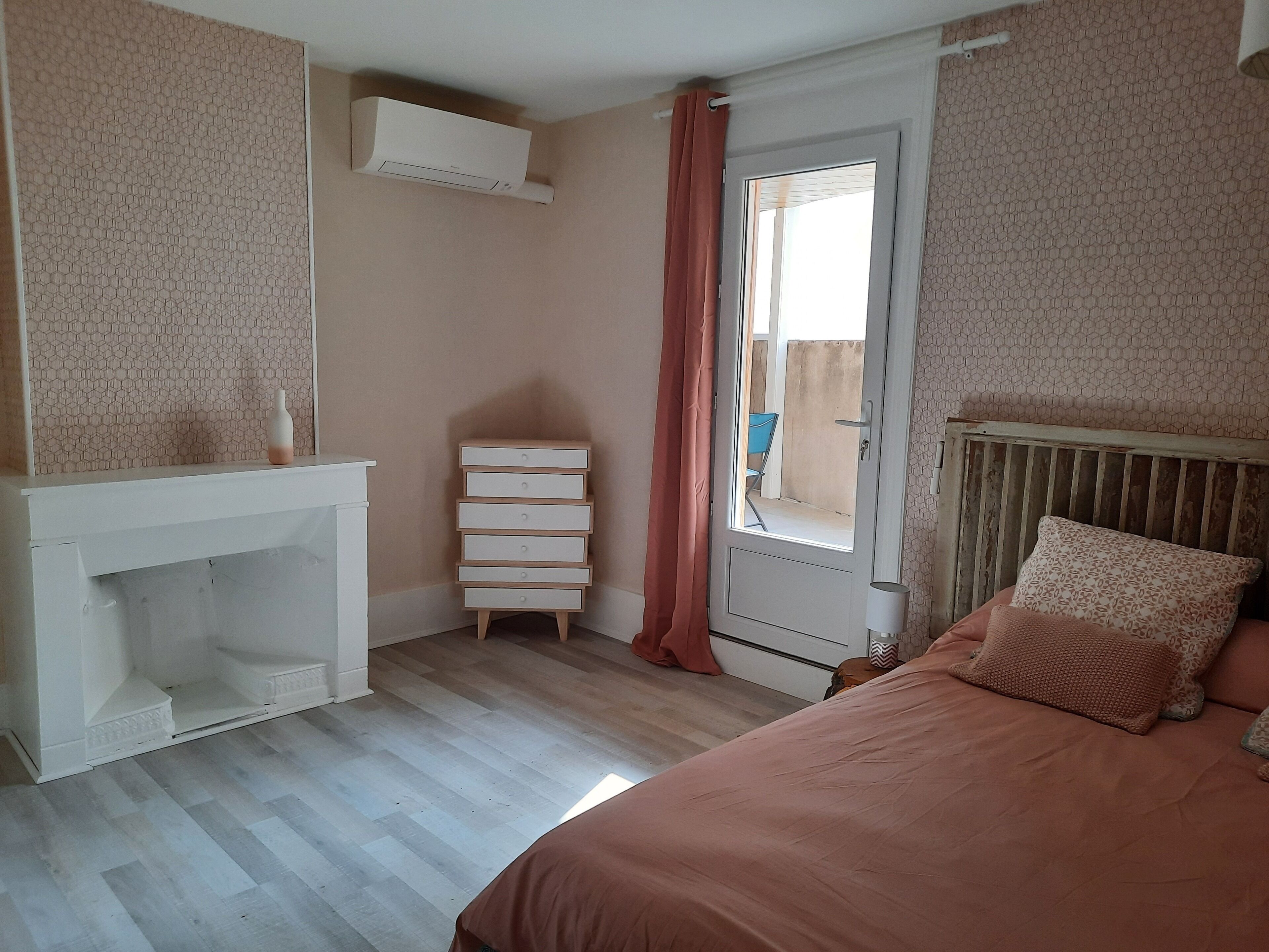 Un dormitorio con cama, cómoda, ventana con cortinas y radiador.