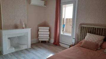 Un dormitorio con cama, cómoda, ventana con cortinas y radiador.