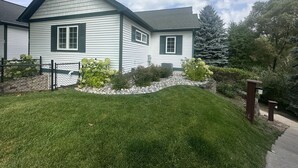 A two-story house with a sloped roof, green shutters, and a well-maintained lawn.