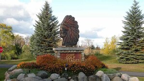 A stop sign, a Native American headdress statue, and a sign for Chief Golf Cottages.