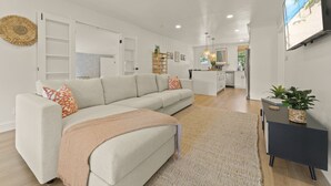 Ein modernes Wohnzimmer mit einer Couch, einem Couchtisch und einem an der Wand montierten Fernseher.