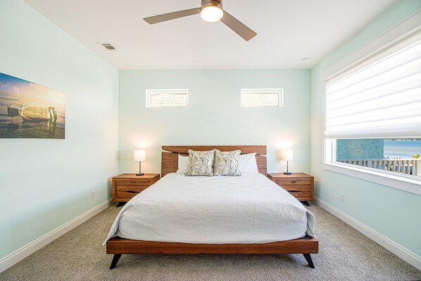 A bedroom with a bed, two bedside tables, a ceiling fan, and a window with blinds. - Hart’s Landing-Canal Front Home (Navarre)