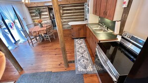 A rustic cabin-style kitchen with wooden cabinets, a stainless steel sink, and a modern stove. - Cozy Cabin Natural Bridge VA (Natural Bridge Station)