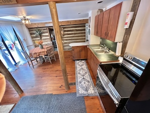 Una cocina de estilo rústico tipo cabaña, con gabinetes de madera, un lavamanos de acero inoxidable y una estufa moderna.