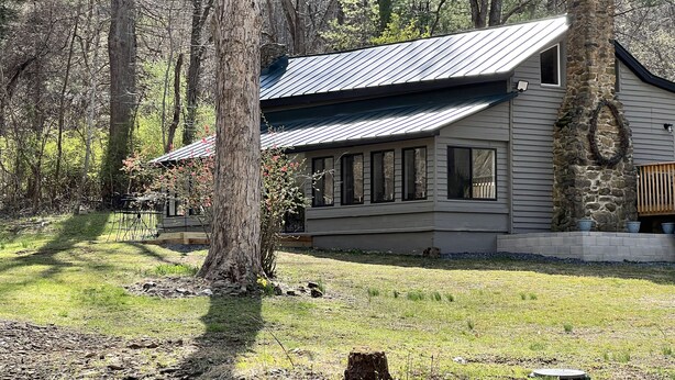 A house with a stone chimney, large windows, and a metal roof, surrounded by trees. - Cozy Cabin Natural Bridge VA (Natural Bridge Station)