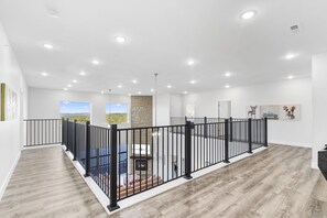 A spacious interior with a wooden floor, a black metal railing, and a fireplace. - Lake View Retreat with Indoor Pool, Theatre, Game Room & Free Daily Tickets (Kimberling City)