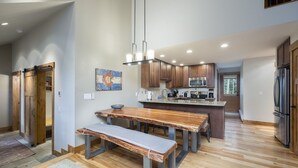A modern kitchen with wooden cabinets, a stainless steel refrigerator, and a central island with a sink and microwave. - Ski Hill Ridge on Peak 7 with Epic Views! (Breckenridge)