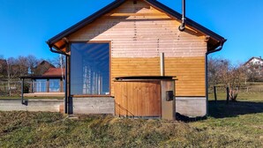 Una cabaña de madera con un amplio portón corredero, una chimenea y un pequeño porche.