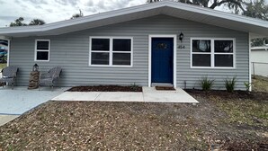 Une maison de plain-pied avec une porte d’entrée bleue, deux fenêtres et une boîte aux lettres.