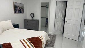 Une chambre à coucher avec un lit, une commode, une porte et un couloir.