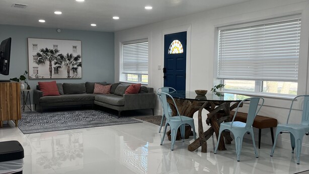 Un salon moderne avec un canapé d’angle, une table basse en verre et des fauteuils bleu clair.